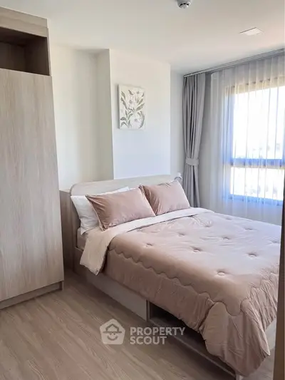 Cozy bedroom with soft lighting, modern decor, and large window for natural light.