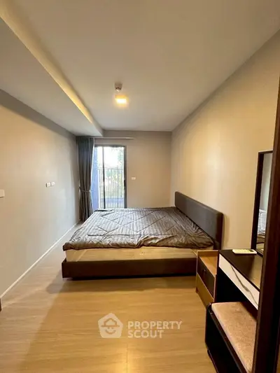 Spacious bedroom with modern furnishings and natural light from large window.