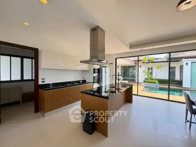 Luxurious modern kitchen with island and pool view, featuring sleek cabinetry and ample natural light.