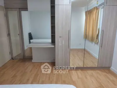 Spacious bedroom with mirrored wardrobe and wooden flooring