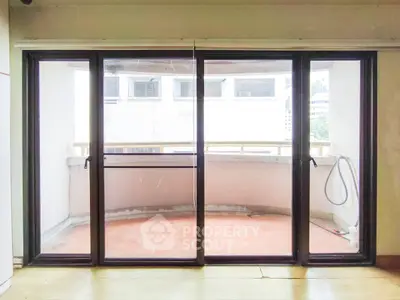 Spacious balcony with sliding glass doors and urban view, perfect for relaxation.