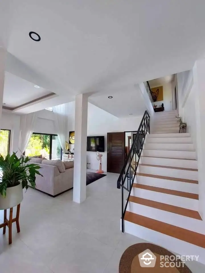 Elegant open-plan living space with high ceilings, modern staircase, and tasteful decor, perfect for sophisticated urban living.