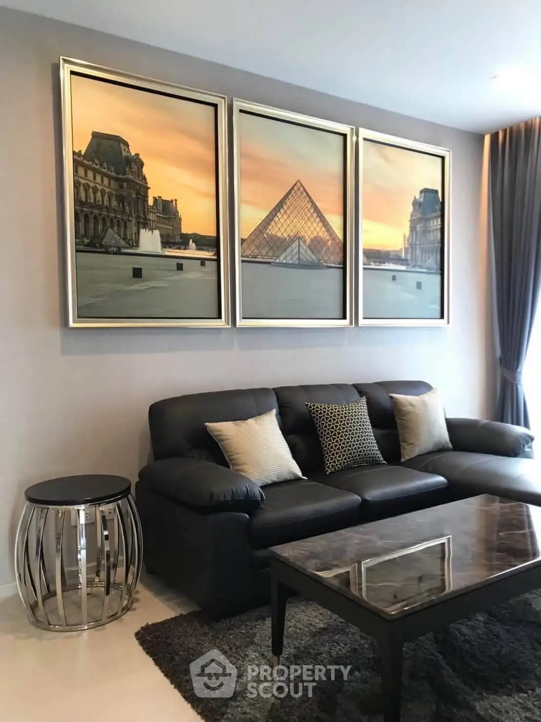 Stylish living room with elegant decor and modern furniture, featuring a black leather sofa and artistic wall art.