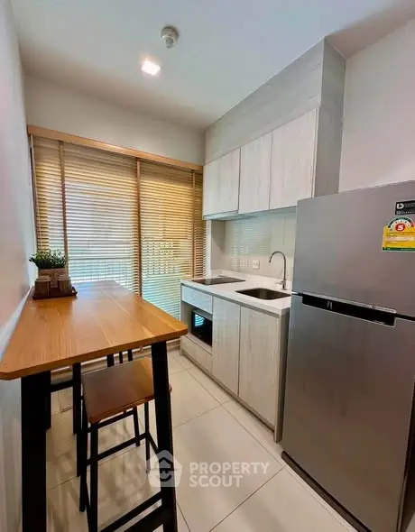 Modern kitchen with sleek cabinetry, stainless steel fridge, and cozy dining area.