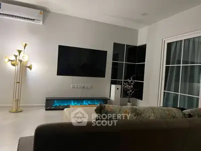 Modern living room with stylish decor, featuring a wall-mounted TV, elegant lighting, and a cozy sofa.