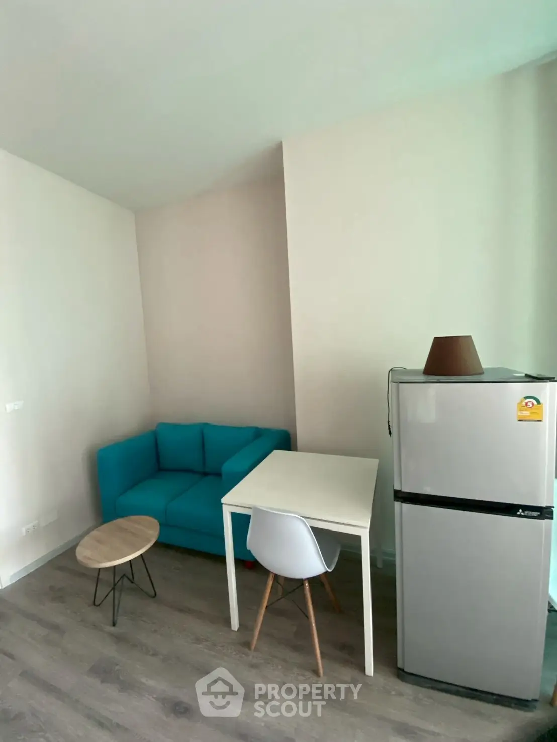 Cozy living area with modern furniture and compact fridge in a stylish apartment.