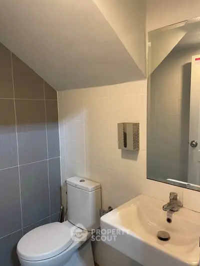 Compact modern bathroom with sleek fixtures and neutral tiles.