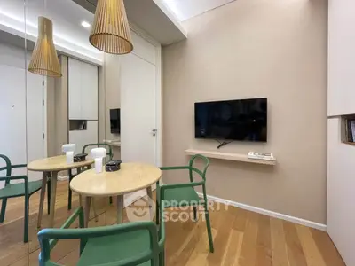 Modern living room with minimalist design, featuring a wall-mounted TV, stylish chairs, and wooden flooring.