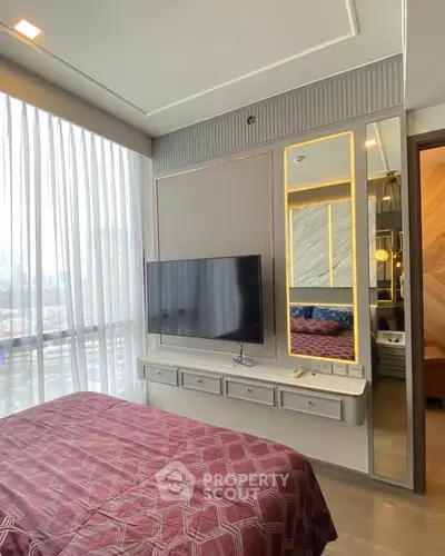 Modern bedroom with large window and wall-mounted TV in a stylish apartment.