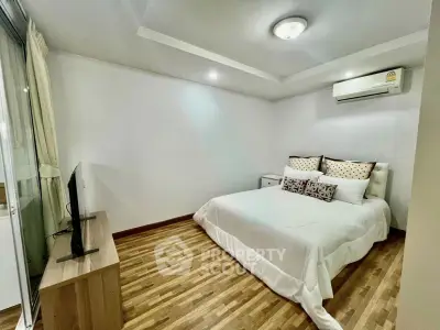 Modern bedroom with wooden flooring and air conditioning in a stylish apartment.