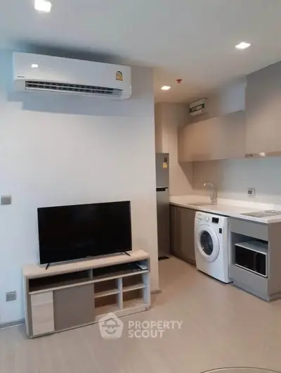 Modern apartment interior with sleek kitchen and living area featuring air conditioning and appliances.