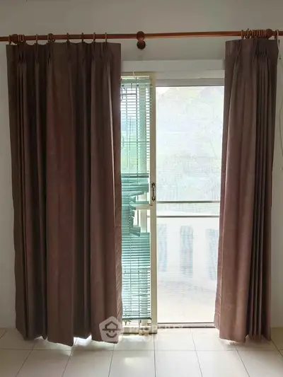 Spacious room with large window and elegant curtains, offering ample natural light and a serene view.