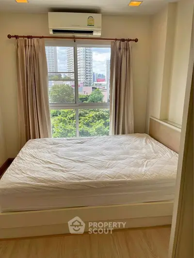 Cozy bedroom with large window offering city and greenery views, featuring a comfortable bed and air conditioning.