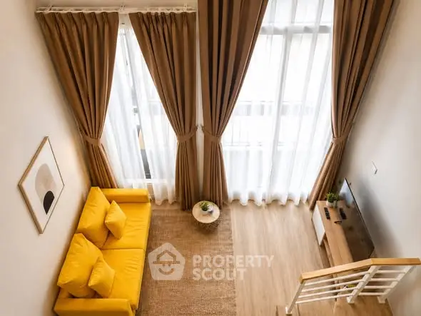 Modern living room with high ceilings, yellow sofa, and large windows with elegant curtains.