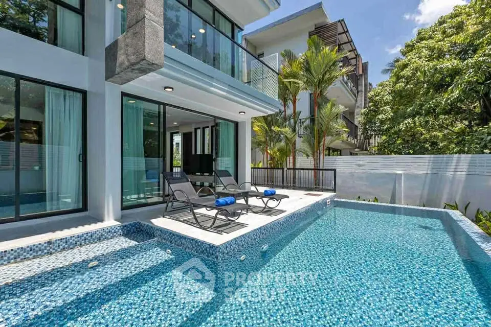 Luxurious modern home with private pool and sun loungers in tropical setting.