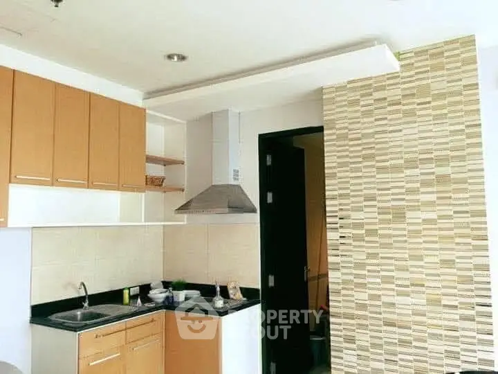 Modern kitchen with sleek cabinets and stylish backsplash in a cozy apartment.
