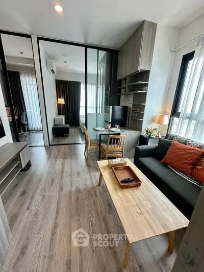 Modern living room with sleek design, featuring wooden flooring, stylish furniture, and ample natural light.
