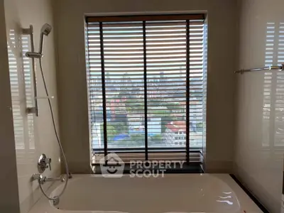 Luxurious bathroom with city view from large window and modern bathtub.