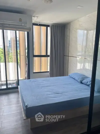 Modern bedroom with large windows and blue bedding in a stylish apartment