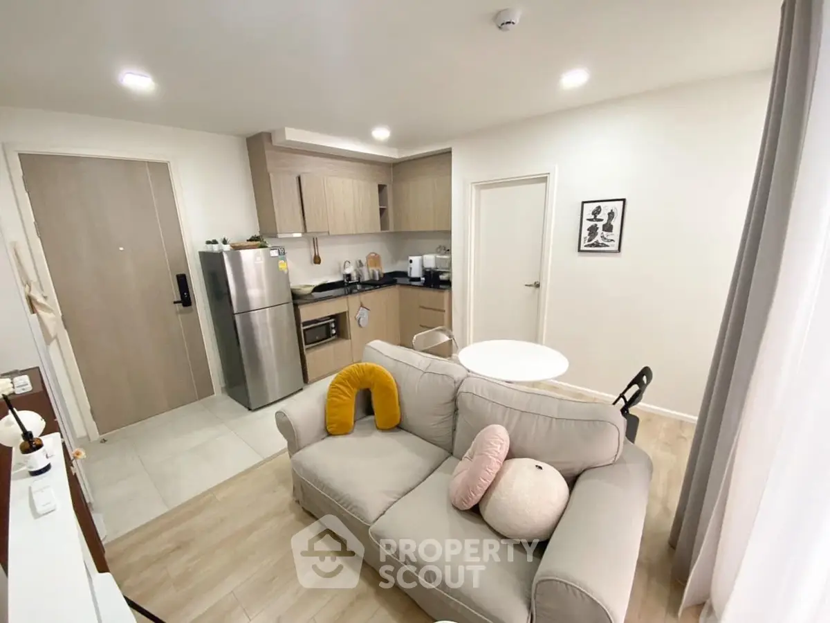 Modern open-layout kitchen and living room with cozy decor and stainless steel appliances.
