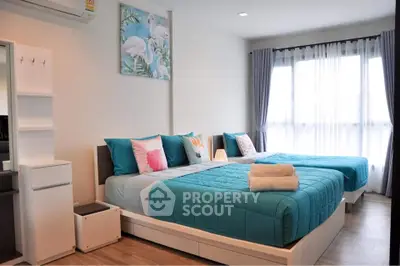 Modern bedroom with twin beds, stylish decor, and natural light from large windows.