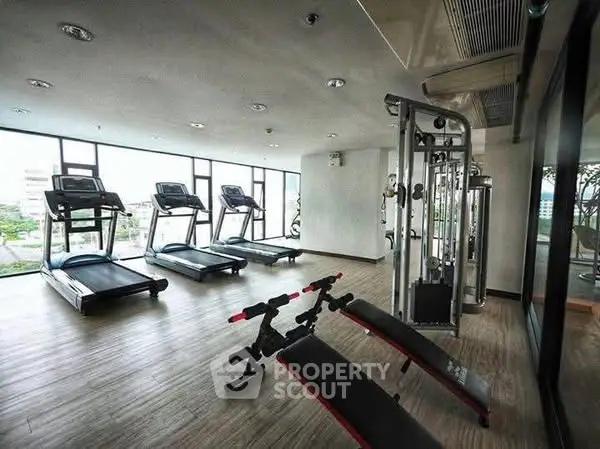 Modern gym with state-of-the-art equipment and large windows offering city views.