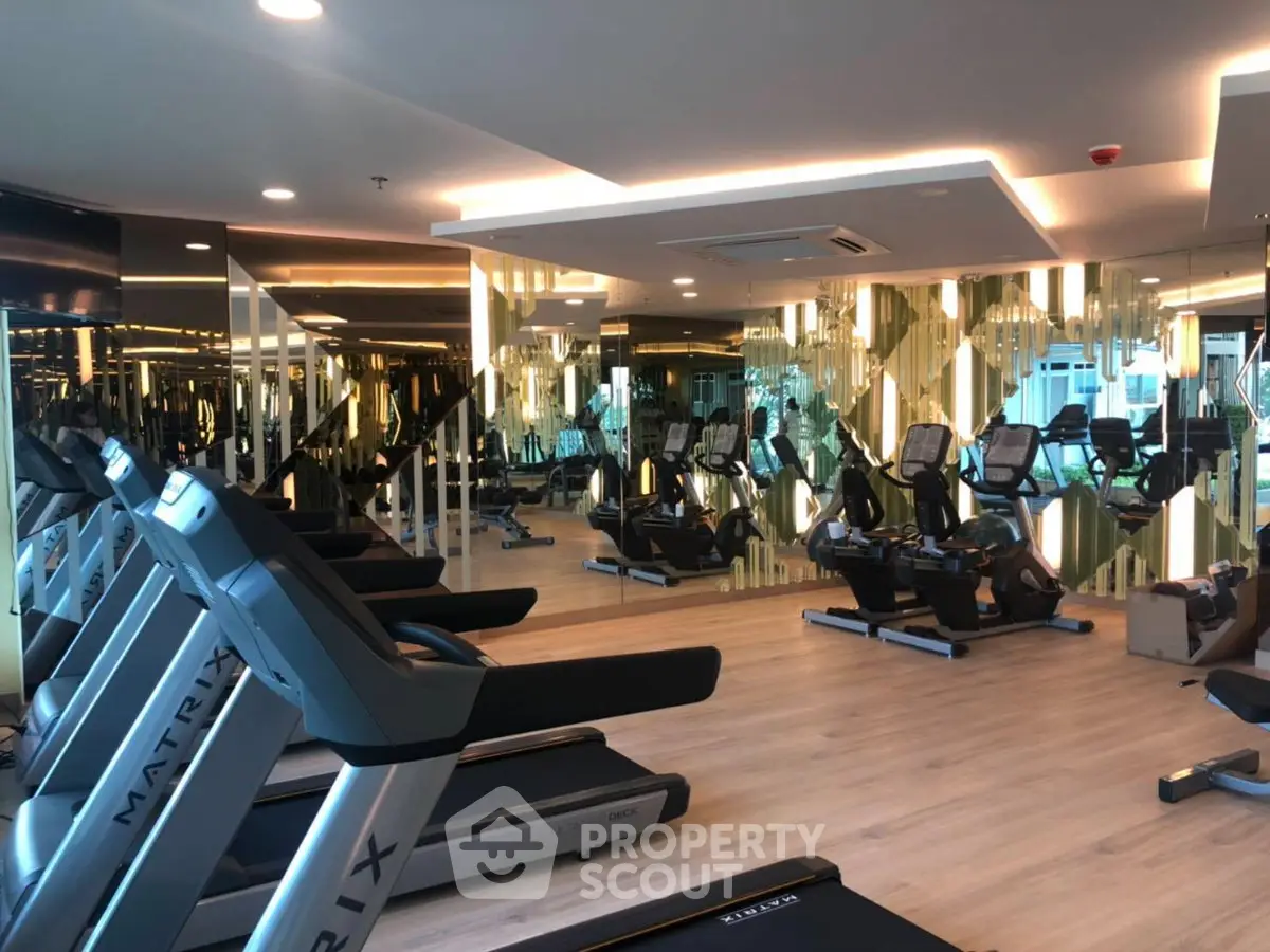 Luxurious modern gym with state-of-the-art equipment and mirrored walls in a high-end residential building.