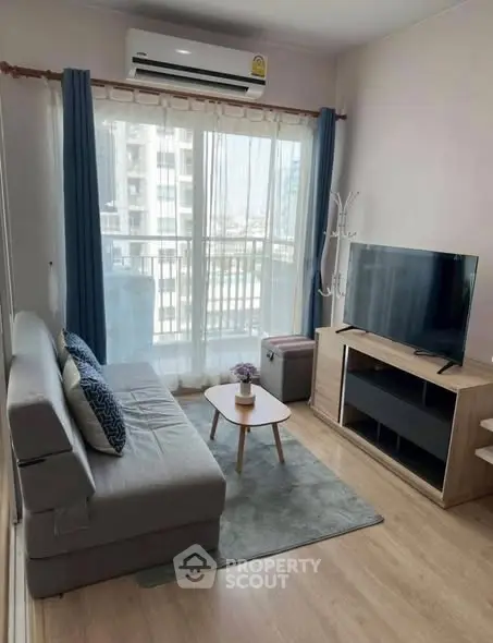 Cozy living room with modern furniture and natural light from balcony.