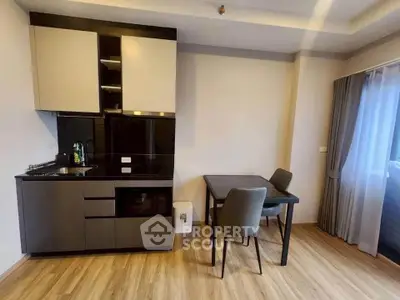 Modern kitchen with sleek cabinetry and dining area in a cozy apartment setting.