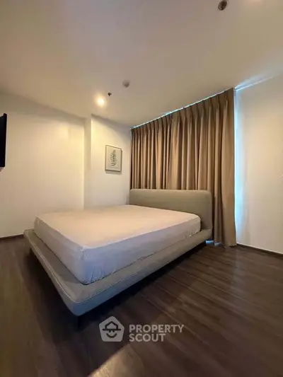 Spacious bedroom with modern design and elegant flooring, featuring a cozy bed and stylish curtains.