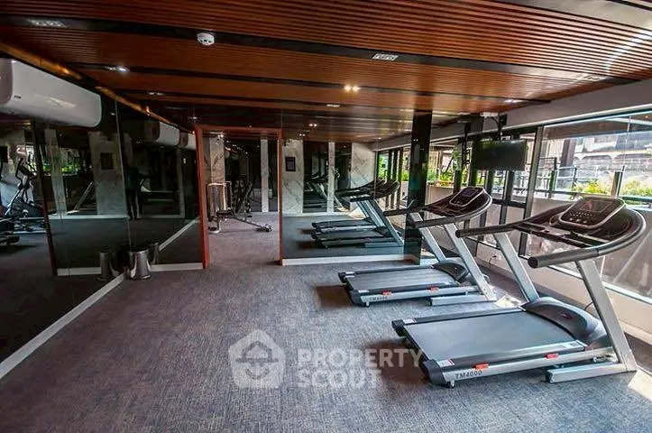 Modern gym with treadmills and mirrored walls in luxury apartment building.