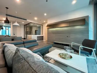 Spacious modern living room with sleek furniture and open kitchen layout in luxury apartment.