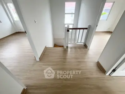 Bright and airy hallway with wooden flooring and white walls, leading to multiple rooms.
