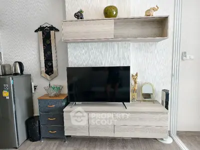Modern living room with sleek TV stand, decorative shelves, and compact fridge.