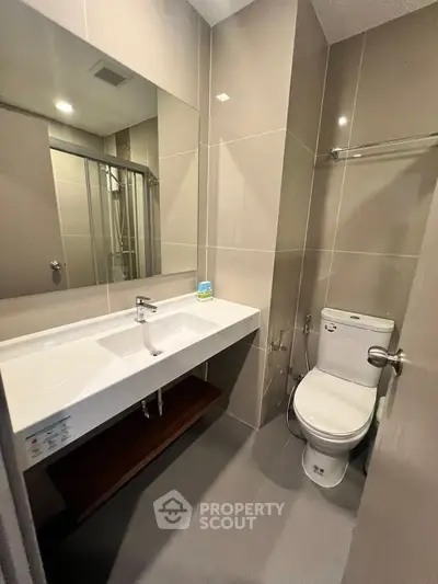 Modern bathroom with sleek fixtures and spacious shower in contemporary apartment.