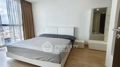 Modern bedroom with large window and stylish furnishings in a high-rise apartment.