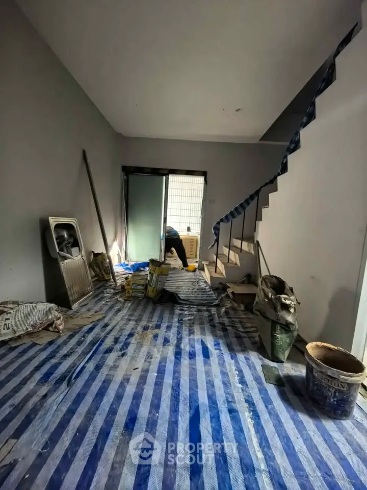Under-construction interior with staircase and protective floor covering, ideal for renovation enthusiasts.