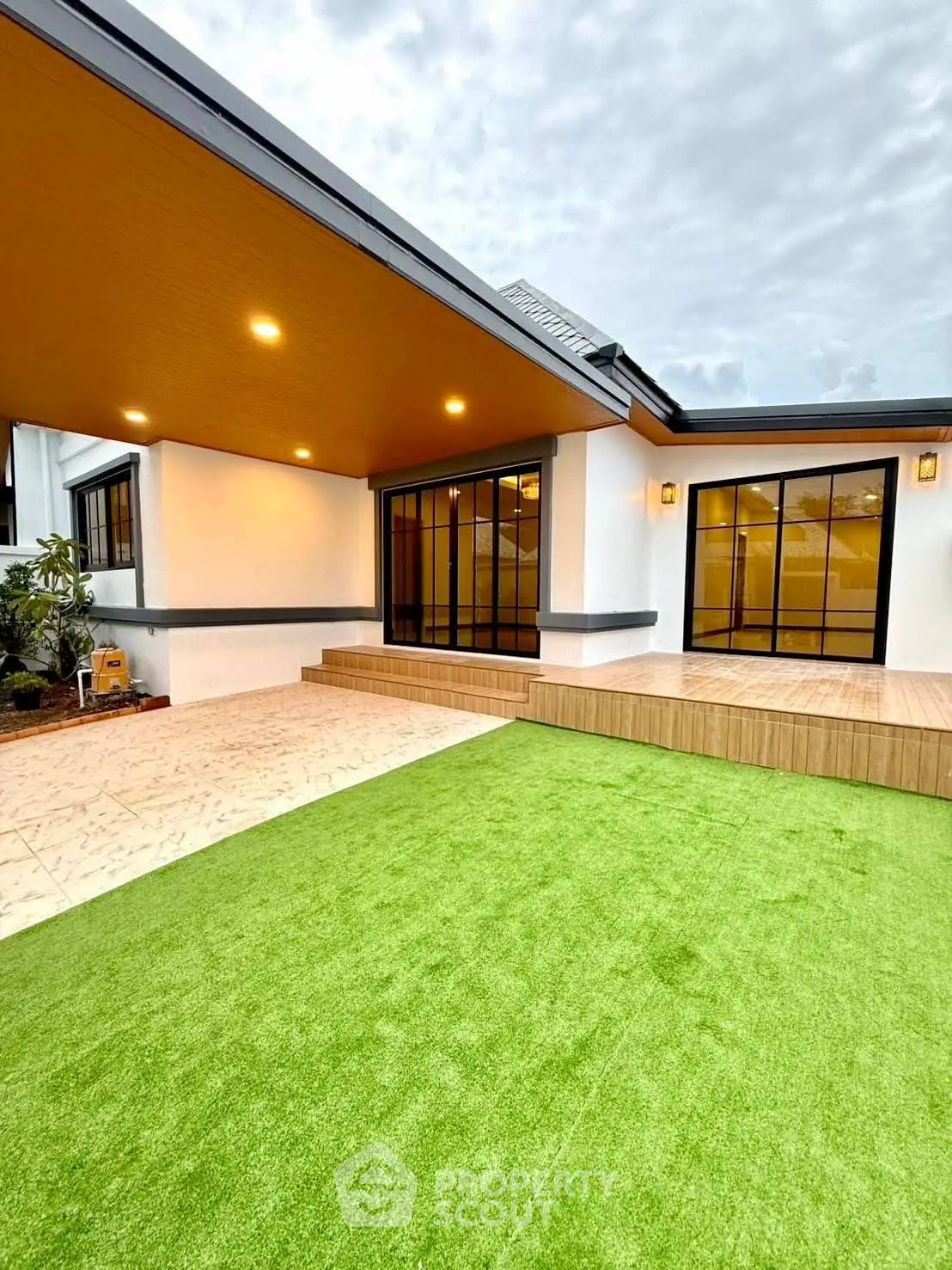 Modern home exterior with spacious patio and lush green lawn