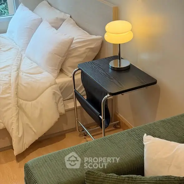 Cozy bedroom with modern lamp and stylish side table, perfect for relaxation.