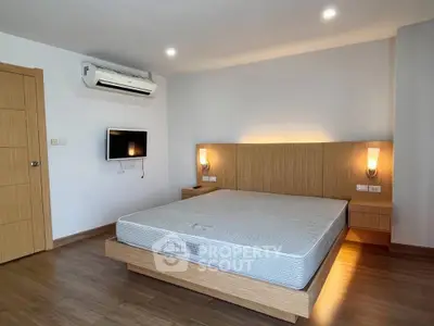 Modern minimalist bedroom with wooden flooring and wall-mounted TV