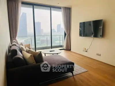 Modern living room with large windows offering city skyline view, featuring a cozy sofa and wall-mounted TV.
