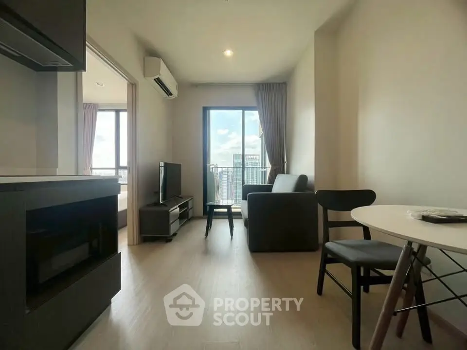 Modern living room with balcony view in a high-rise apartment, featuring sleek furniture and natural light.