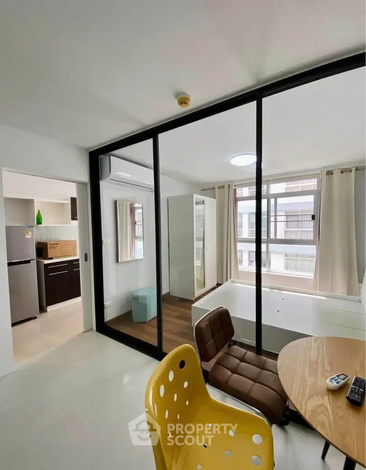 Modern apartment with glass partition, cozy study area, and bright natural light.