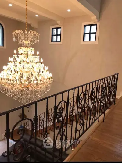 Luxurious interior with grand chandelier and elegant railing overlooking spacious living area.