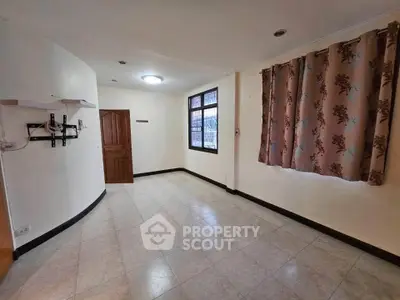 Spacious empty room with tiled floor and large window, ideal for customization.