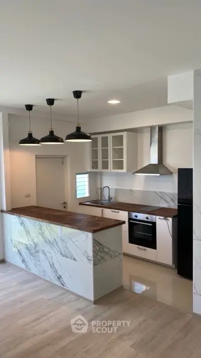 Modern kitchen with marble accents, sleek cabinetry, and stainless steel appliances in a stylish open layout.