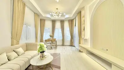 Elegant living room with modern decor and large windows, featuring a cozy seating area and stylish lighting.