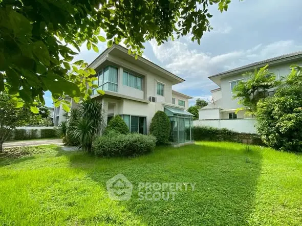 Charming two-story house with lush green garden and modern architecture.