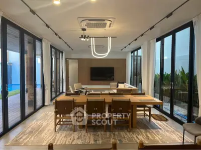 Spacious modern living room with elegant dining area and large windows overlooking greenery.
