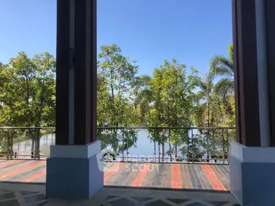 Stunning balcony view overlooking lush greenery and serene water, perfect for relaxation.